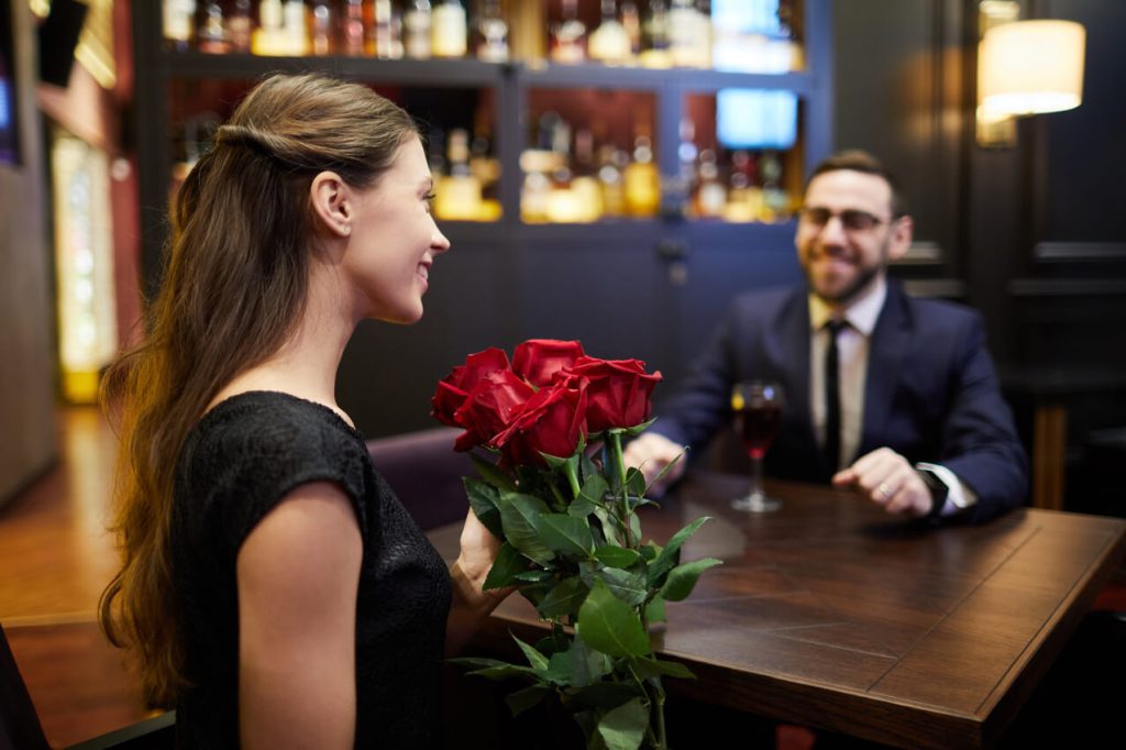 a guy dates a milf from chicago in a fancy restaurant while she is holding some flowers