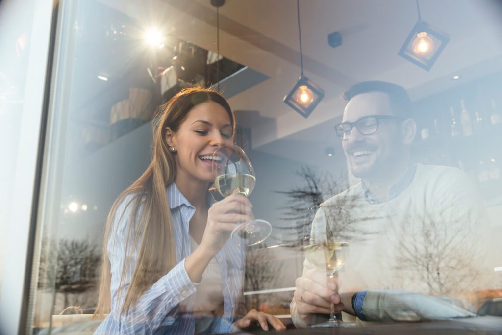 a milf from austin dating a younger man on a bar while they are drinking a wine