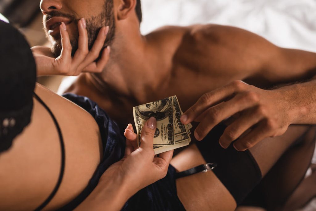 an el paso escort being intimate with a man in bed while being given her money