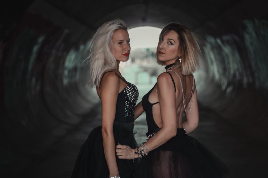two new york city girls wearing black sexy dress in a tunnel