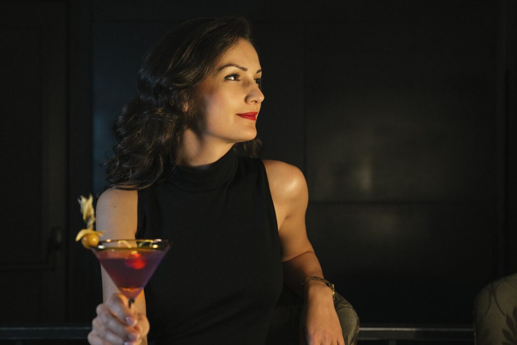 a woman from fort worth is in a nightclub holding a glass of cocktail
