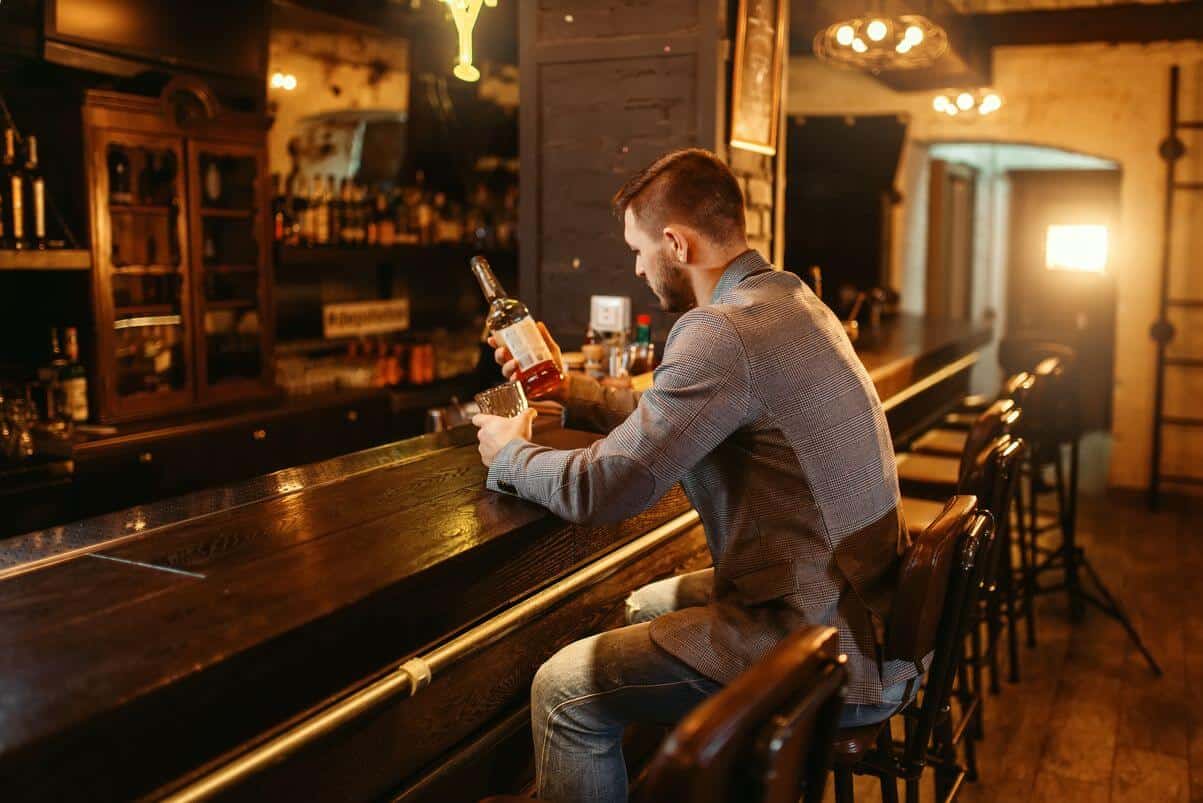 a single guy holding a bottle of liquor on a bar in san francisco